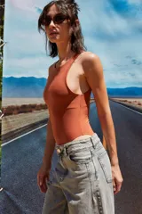 Body color marrón oscuro, confeccionado en microfibra, con escote delantero y trasero cerrado, cuerpo embolsado y gancho corsetero regulable en la entrepierna.