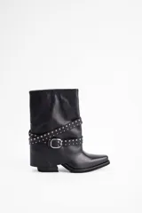 Bota de caña media confeccionada en cuero vacuno negro, con diseño de estilo western. Presenta una puntera estilizada, taco bajo y una correa decorativa con tachas metálicas y hebilla plateada que rodea el tobillo.