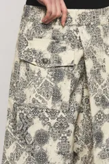 Bermuda de gabardina de calce relajado, tiro largo, con estampado estilo paisley en tonos beige y negro, y bolsillos delanteros estilo cargo con broches metálicos.