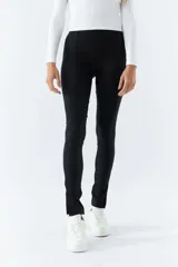 Pantalón negro de tiro alto, corte ajustado y aberturas en los tobillos.