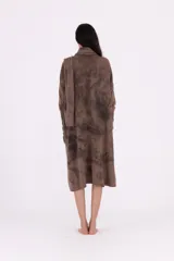 Vestido de tejido de punto gris oscuro con efecto tie-dye o marmolado, silueta amplia y largo midi. Posee cuello tortuga caído y mangas largas con abertura para el pulgar.