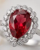 Anillo de plata con piedra central roja en corte gota, rodeada por circonias cúbicas.