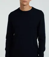 Suéter negro de punto con cuello redondo y mangas largas. Diseño con líneas horizontales en relieve.