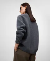 Jersey de lana gris melange, con cuello en V y manga larga. Presenta remates en canalé en puños y bajo.