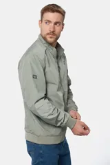 Campera liviana de color verde grisáceo, con cierre frontal, cuello alto y puños elásticos. Presenta un pequeño parche con logo en el pecho.