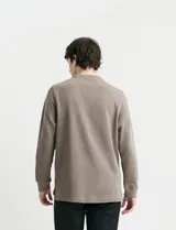 Remera de manga larga con cuello polo, confeccionada en tejido de punto canalé francés. Presenta abotonadura frontal con botones de madera y detalles a contratono en la cartera y el interior del cuello.