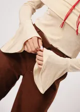 Blusa beige con hombros descubiertos, mangas largas acampanadas y confeccionada en tela stretch con lurex.