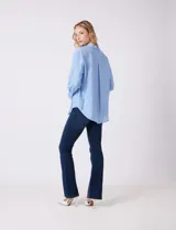 Camisa de algodón con estampado de rayas verticales finas en color azul claro. Tiene cuello con solapa, escote en V y cierre frontal con botones.