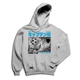 Canguro gris con capucha y bolsillo frontal tipo canguro. Presenta un estampado gráfico estilo manga en el frente con motivos de fútbol y texto en japonés y en inglés.