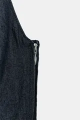 Mono largo de denim color azul oscuro, con escote redondo, tirantes cruzados en la espalda, bolsillos delanteros y pernera recta. Cuenta con cierre lateral con cremallera.