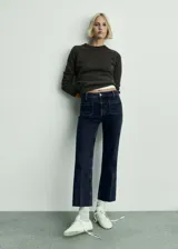 Jeans de tiro medio con diseño acampanado y corte cropped. Presenta bolsillos de parche en la parte delantera y trasera, cierre frontal con cremallera y botón, y trabillas para cinturón.