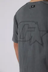 Remera de algodón gris con efecto acid wash, corte regular, mangas cortas y cuello redondo. Cuenta con un pequeño bordado tono sobre tono en el pecho y una etiqueta lateral distintiva de la marca en el ruedo.