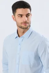 Camisa de lino de manga larga en color beige, con cuello camisero, cierre frontal de botones y un bolsillo ojal en el pecho.