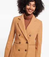Blazer de corte sastrero en tejido polivelour color tostado. Presenta diseño cruzado con doble botonadura frontal, solapas clásicas y bolsillos laterales. De manga larga y estructura entallada.