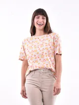 Remera de manga corta color beige con estampado de bananas en tonos amarillo, naranja y rosado.