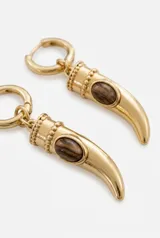 Aro colgante dorado con dije en forma de cuerno texturizado y piedra sintética incrustada.