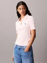 Chomba de Calvin Klein Jeans confeccionada en tejido de algodón con textura acanalada. Presenta cuello tipo polo con cartera de dos botones, mangas cortas y una insignia distintiva de la marca aplicada en el pecho.
