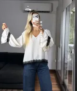 Blusa de tela cey color bordó, con escote en V y mangas largas abullonadas que terminan en puños con detalle de encaje y volados.