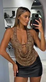 Top halter de color marrón con escote profundo y diseño drapeado. Presenta un estampado de líneas curvas con lentejuelas brillantes integradas en el tejido.