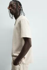 Camiseta de manga corta color crema, con cuello redondo y tejido texturizado con estructura.