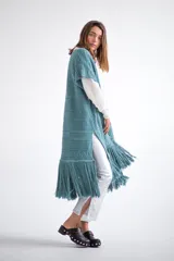 Chaleco largo de tejido de punto color azul verdoso, sin mangas y con flecos en el ruedo. Presenta calados con diseño geométrico.