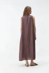 Vestido largo sin mangas de color celeste, con cuello camisero, cierre frontal con botones y bolsillos laterales.