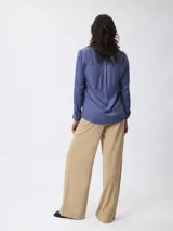 Pantalón de corte recto y pierna ancha, color beige, con cintura de tiro medio y cierre frontal.