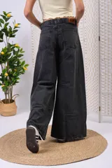 Pantalón wide leg de denim negro desgastado, de tiro medio con doble botón y corte amplio en las piernas con costuras frontales.