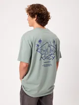 Remera blanca Rusty de corte holgado, con cuello redondo y mangas cortas. Presenta un estampado en la espalda de estilo veraniego con palmeras, una tabla de surf y letras alusivas a la marca.