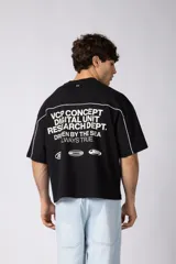 Remera gris oscuro de corte boxy, con mangas cortas y cuello redondo. Cuenta con un diseño gráfico frontal con líneas blancas y la palabra 'CONCEPT' estampada.