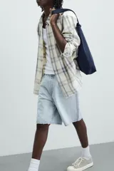 Bermuda de denim de algodón, color verde claro lavado, de corte recto y tiro medio. Presenta cinco bolsillos y cierre frontal con cremallera y botón.