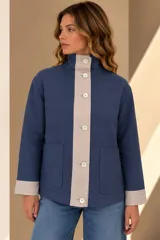 Campera marrón de lino con diseño bicolor, con una franja central gris claro que incluye botones de nácar. Cuenta con cuello alto, mangas largas con puños grises, bolsillos frontales aplicados y silueta amplia.