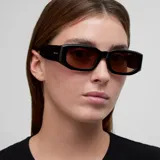 Lentes de sol con montura geométrica rectangular de color negro y lentes polarizadas en tono marrón. Presentan un diseño con detalles biselados en el marco.