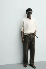 Camiseta relaxed fit color crema, con cuello redondo tipo panadero y cierre frontal de tres botones. Manga larga y acabados en rib.