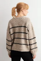 Sweater de punto con textura, color beige melange con rayas horizontales negras. Presenta cuello redondo, mangas largas y corte holgado.