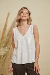 Musculosa de lentejuelas doradas con doble escote en V, tanto en el frente como en la espalda. Presenta breteles anchos y un corte levemente acampanado.