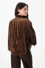 Camisa de manga larga confeccionada en terciopelo con acabado arrugado. Presenta cuello clásico, cierre frontal con botones y puños abotonados.