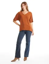 Blusa de silueta fluida con escote en V, manga japonesa corta y costura central vertical en el frente. Confeccionada en tejido de punto con acabado mate, presenta un diseño con largo asimétrico, siendo más larga en la espalda.