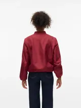 Campera bomber corta color bordó, con cuello redondo, cierre frontal de cremallera y bolsillos delanteros. Está completamente forrada.