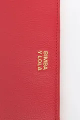 Billetera mediana de estructura rígida confeccionada en piel vacuna negra, con cierre de cremallera, tirador de tejido con logo y logo metálico frontal.