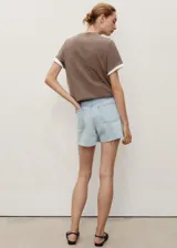 Short de denim celeste claro, con tiro medio, diseño de cinco bolsillos, presillas para cinturón y bajo deshilachado con pequeña abertura lateral.