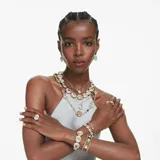 Brazalete abierto dorado con tres cristales facetados de talla cojín: verde, rosa y azul.