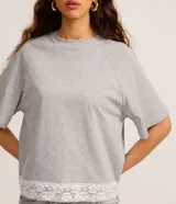 Remera femenina gris de algodón con cuello redondo, manga raglán corta y ruedo con detalle de encaje blanco.