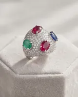 Anillo de plata 925 con diseño bombe, completamente pavimentado con circonias blancas y decorado con cuatro piedras naturales ovaladas: rubí, esmeralda y zafiro azul.