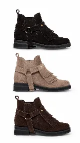 Botinetas de gamuza color marrón oscuro con detalle de flecos en el empeine y correa con tachas metálicas doradas. Poseen suela plana y diseño de caña baja.