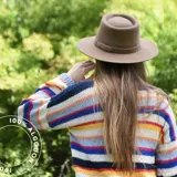 Sombrero marrón de ala ancha confeccionado en paño de lana afieltrada a mano, con cinta decorativa del mismo material alrededor de la copa.