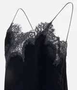 Vestido corto de terciopelo negro, estilo slip dress, con escote corazón, breteles finos y detalles de encaje en el escote y en el ruedo asimétrico con terminación en punta lateral.