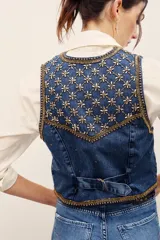 Chaleco de denim azul con bordados metalizados y pedrería en la parte superior delantera, escote en V y cierre frontal con botones metálicos.