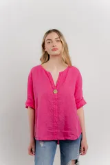 Blusa holgada de lino color verde brillante, con cuello mao abierto y manga corta enrollada. Presenta bordados estilo paisley en tono a tono y un botón de madera en el escote.