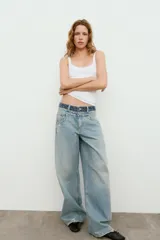 Jeans de tiro medio con cinco bolsillos, cintura doble a contraste y detalles de rotos. Cierre frontal con cremallera y botones metálicos.
